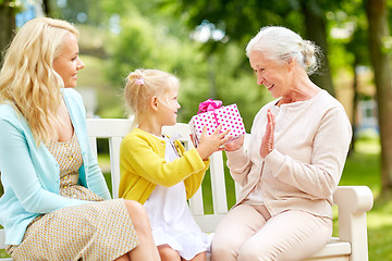 Image showing happy family giving present to grandmother at park