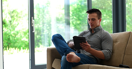 Image showing Man is Laying on Couch at Home and Using Tablet