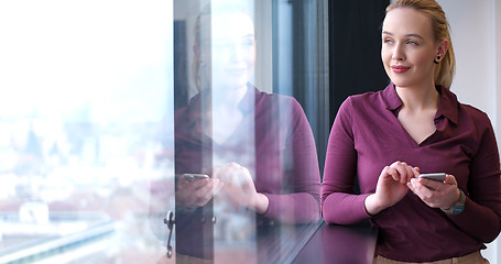 Image showing Elegant Woman Using Mobile Phone by window in office building