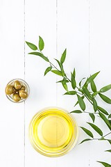 Image showing Olive oil and olive branch on the wooden table