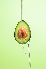 Image showing Fresh avocado and oil on green background