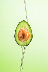 Image showing Fresh avocado and oil on green background