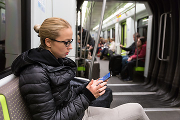 Image showing Young girl reading from mobile phone screen in metro.