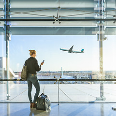 Image showing Young woman waiting at airport, looking through the gate window.