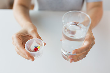 Image showing close up of hands with pills and glass of water