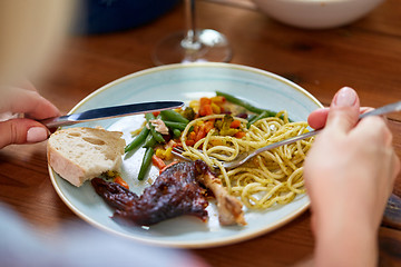 Image showing hands of woman eating pasta and roast chicken