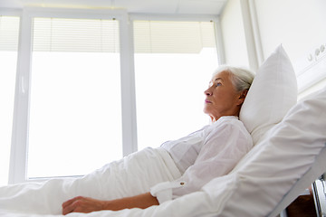 Image showing sad senior woman lying on bed at hospital ward