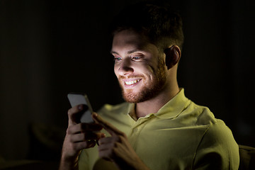 Image showing happy young man with smartphone at night