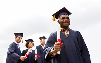 Image showing happy students in mortar boards with diplomas