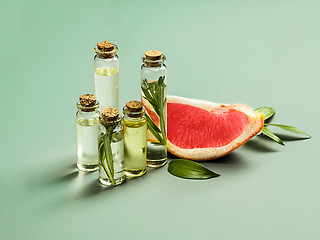 Image showing Essential oil in glass bottle with fresh, juicy grapefruit and green leaves-beauty treatment.