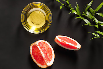 Image showing Essential oil in glass bottle with fresh, juicy grapefruit and green leaves-beauty treatment.