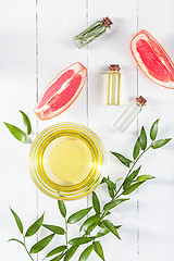 Image showing Essential oil in glass bottle with fresh, juicy grapefruit and green leaves-beauty treatment.