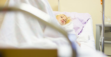 Image showing Bedridden female patient recovering after surgery in hospital care.