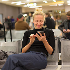 Image showing Lady using smart phone while waiting at airpot departure gates.