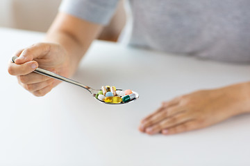 Image showing close up of female hand holding spoon with pills