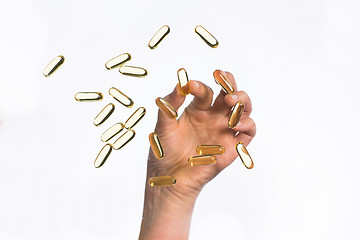 Image showing hand picking cod liver oil capsules up