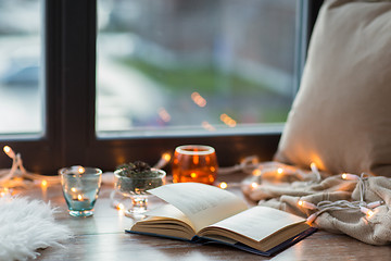 Image showing book, garland lights and candles on window sill