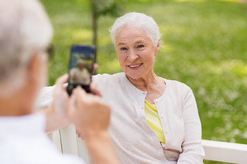 Image showing old woman photographing man by smartphone in park