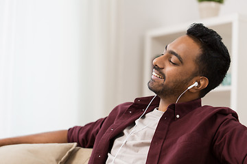 Image showing happy man in earphones listening to music at home