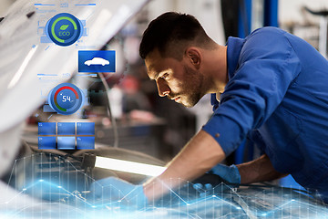 Image showing mechanic man with lamp repairing car at workshop