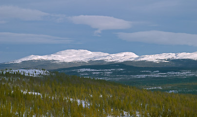 Image showing White mountain with winter snow, dark sky and clouds, pine woods, Vålådalen, north Sweden