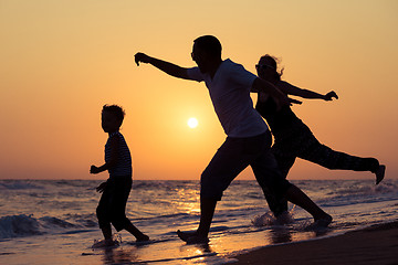 Image showing Father mother and  son  playing on the beach at the sunset time.