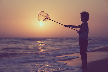 Image showing One happy little boy playing on the beach at the sunset time.