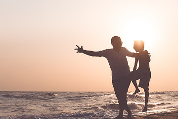 Image showing Father and son  playing on the beach at the sunset time.