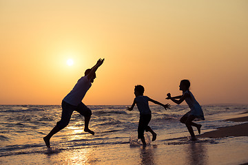 Image showing Father son and daughter playing on the beach at the sunset time.