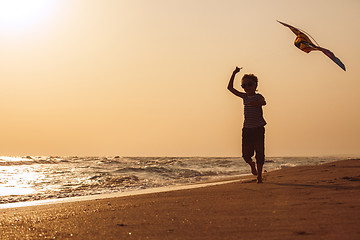 Image showing One happy little boy playing on the beach at the sunset time.