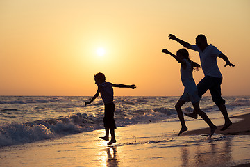 Image showing Father son and daughter playing on the beach at the sunset time.