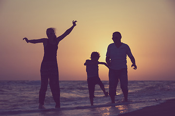 Image showing Father mother and  son  playing on the beach at the sunset time.