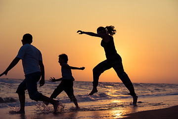 Image showing Father mother and  son  playing on the beach at the sunset time.