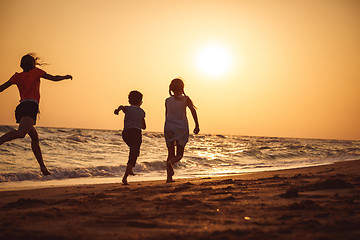 Image showing Happy children playing on the beach at the sunset time.