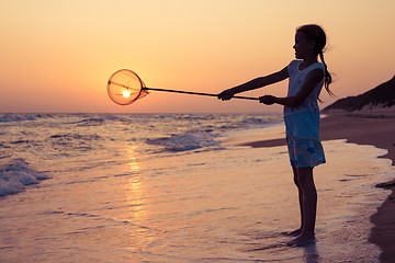 Image showing One happy little girl playing on the beach at the sunset time.