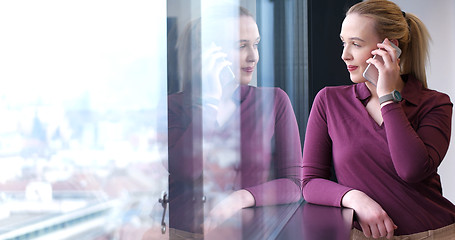 Image showing Elegant Woman Using Mobile Phone by window in office building