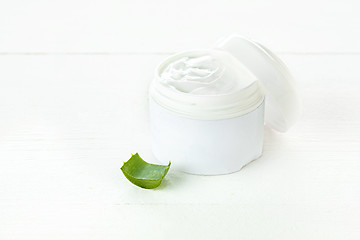 Image showing Opened plastic container with cream and aloe on a white background.