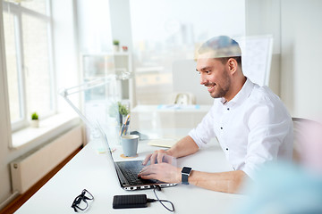 Image showing happy businessman typing on laptop at office