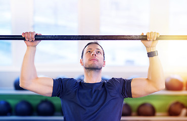 Image showing man exercising on bar and doing pull-ups in gym