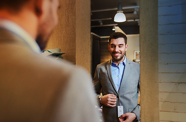 Image showing man trying jacket on at mirror in clothing store