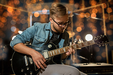 Image showing musician playing guitar at studio over lights
