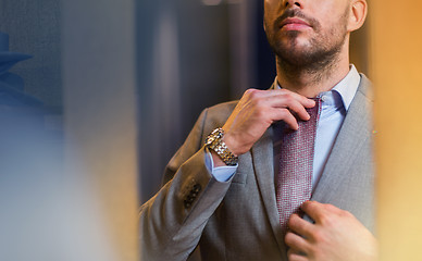 Image showing close up of man trying tie on at mirror