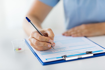 Image showing doctor with medicines and clipboard at hospital