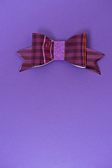 Image showing Pink and red striped bow tie over ultra violet background.