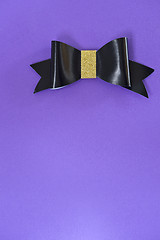 Image showing Black and golden bow tie over ultra violet background.