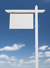 Image showing Blank Real Estate Sign Over A Blue Sky with Clouds.
