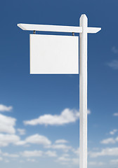 Image showing Blank Real Estate Sign Over A Blue Sky with Clouds.