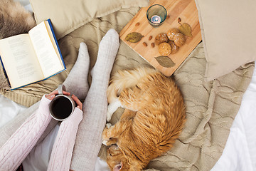 Image showing woman with coffee and red cat sleeping in bed