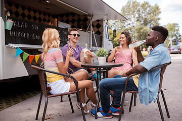 Image showing friends with drinks sitting at table at food truck