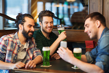 Image showing friends with smartphone drinking green beer at pub